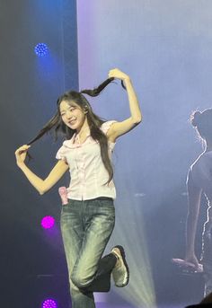 a woman is dancing on stage with her hair in the air