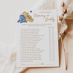 a winnie the pooh baby shower checklist next to a dried flower on a bed