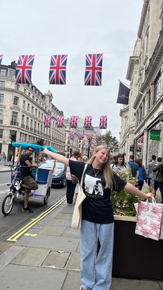 a woman is standing on the sidewalk with her arms in the air