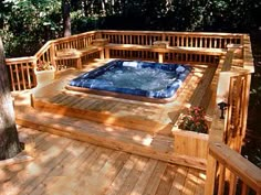 a hot tub sitting on top of a wooden deck next to a tree in the woods