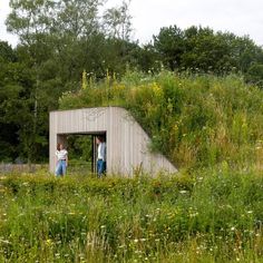 two people standing in the doorway of a building with grass growing on it's roof