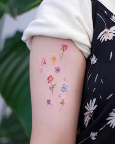 a woman's arm with flowers painted on the back of her left arm and shoulder