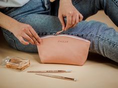 a woman is sitting on the floor with her purse next to some pens and pencils