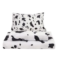 the black and white cow print sheets are folded on top of each other, with two pillows