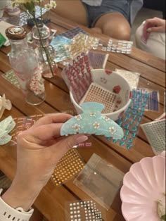 a person holding a piece of crafting material in their hand on a wooden table