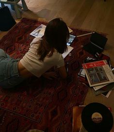 a woman is sitting on the floor with her laptop and papers in front of her