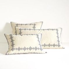 three black and white pillows sitting next to each other on top of a bed in front of a white wall