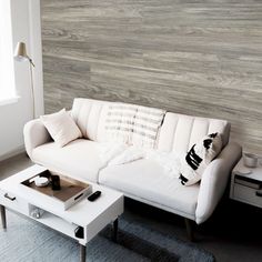 a white couch sitting next to a coffee table on top of a carpeted floor