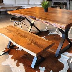 a wooden table sitting on top of a cow hide rug