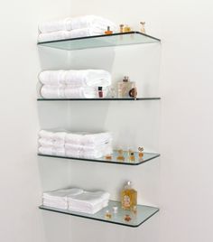 three glass shelves filled with white towels and personal care items