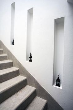 a set of stairs leading up to two lanterns on the wall next to each other