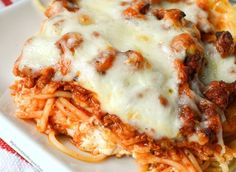 a white plate topped with spaghetti and meat covered in sauce on top of it next to a fork