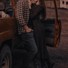 a man and woman standing in the back of a red truck with their arms around each other