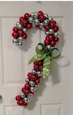 a red and silver christmas ornament wreath on a door with green bow hanging from it