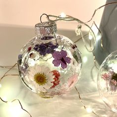 an ornament with flowers on it sitting next to another glass ornament