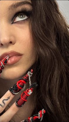 a woman with red and black nail art on her hands, holding a cell phone up to her face