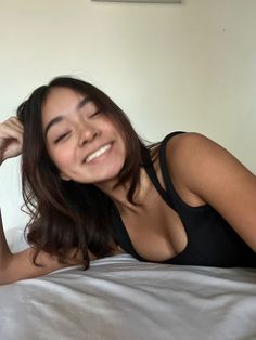 a woman laying on top of a bed smiling