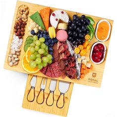 a wooden cutting board with cheese, fruit and crackers on it next to two knives