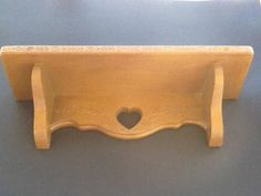 a wooden shelf with a heart cut out on the front and bottom, sitting on a blue surface