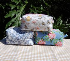 three pillows sitting on top of a table next to each other with flowers and bees on them