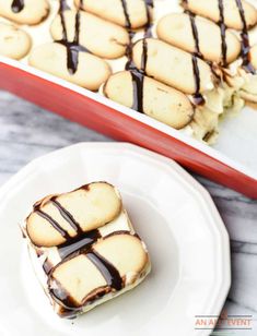 some cookies are sitting on a plate next to a red tray with chocolate drizzled on them