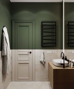 a bathroom with green walls and two sinks on the counter, towel rack in the corner