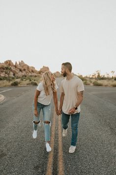 a man and woman walking down an empty road