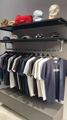 a clothing rack with t - shirts and hats on it