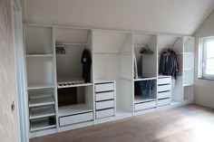 an empty room with white shelves and drawers