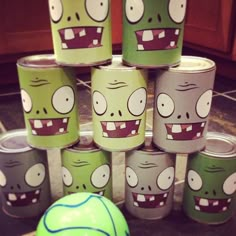 several cans with faces painted on them are stacked next to a green and white ball