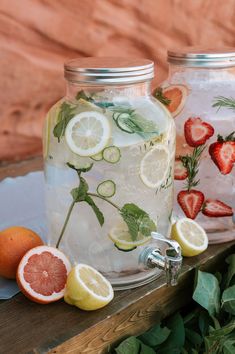 two mason jars with lemons, strawberries and cucumber slices in them