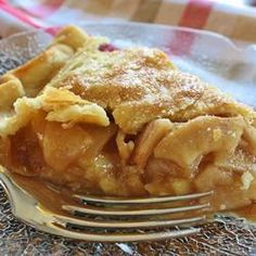 a piece of pie sitting on top of a glass plate with a fork next to it