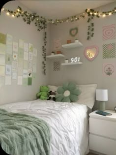 a small bedroom with white walls and green decorations on the ceiling, along with string lights