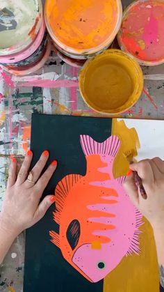 someone is painting a fish on a piece of paper