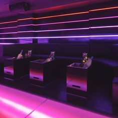 the interior of a restaurant with purple lighting and black booths lined up against the wall