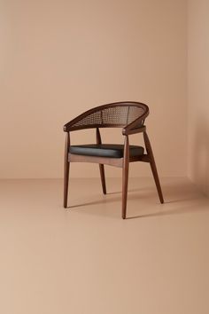 a wooden chair with a black seat and back cushion in front of a beige wall