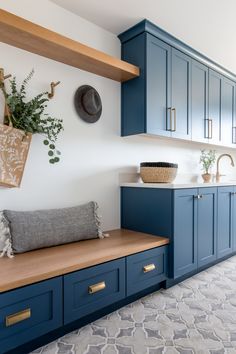 a kitchen with blue cabinets and wooden counter tops in the center is a basket hanging on the wall