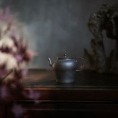 a tea pot sitting on top of a table next to a vase filled with flowers