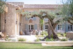 an outside view of a house with trees in the foreground and chairs on the patio