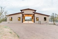 a large building with an open front door in the middle of a dirt lot next to trees