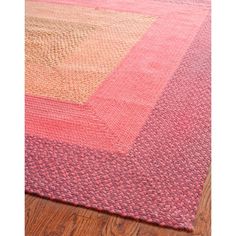 a pink and yellow area rug on a wooden floor with a wood floor in the background