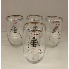 four wine glasses decorated with christmas trees and snowflakes are on a white surface