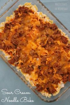 a casserole dish with noodles and meat in it on a blue tablecloth