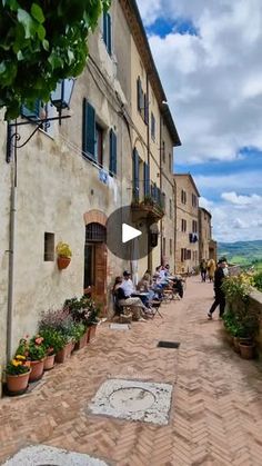 people are sitting at tables in front of an old building with flowers and greenery