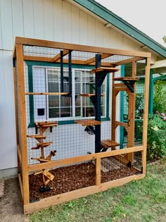 a chicken cage with some birds inside of it on the side of a house in front of a window