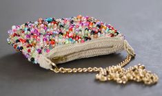 the purse is covered with beads and has a gold chain hanging from it's side