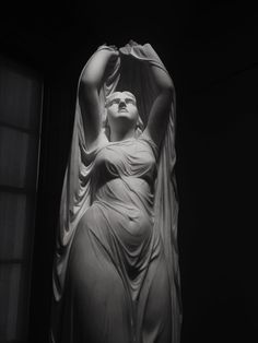 a statue is shown in the dark with its hands on her head and eyes closed