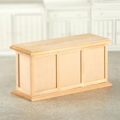 a wooden toy chest sitting on top of a floor next to a white countertop