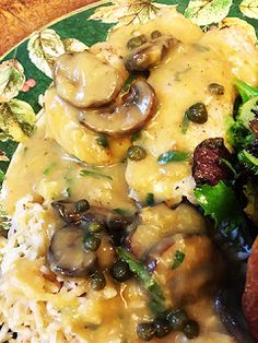 a green plate topped with meat covered in mushroom gravy next to rice and broccoli