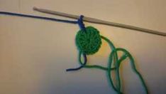 a crochet hook hanging on a wall with a green ball of yarn attached to it